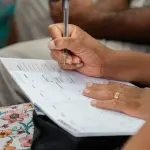 A woman writing in a calendar planner, highlighting organization and time management.