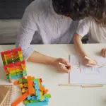 A mother and child drawing with colored pencils at a table, fostering creativity and learning.