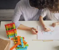 A mother and child drawing with colored pencils at a table, fostering creativity and learning.