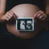 a pregnant woman holding a camera in her hands