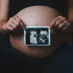 a pregnant woman holding a camera in her hands