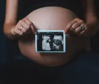 a pregnant woman holding a camera in her hands