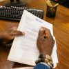 A person signs official divorce documents at an office desk.