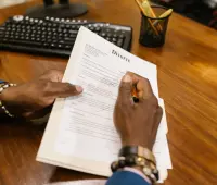 A person signs official divorce documents at an office desk.