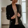 woman in black blazer standing near white wall