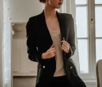 woman in black blazer standing near white wall